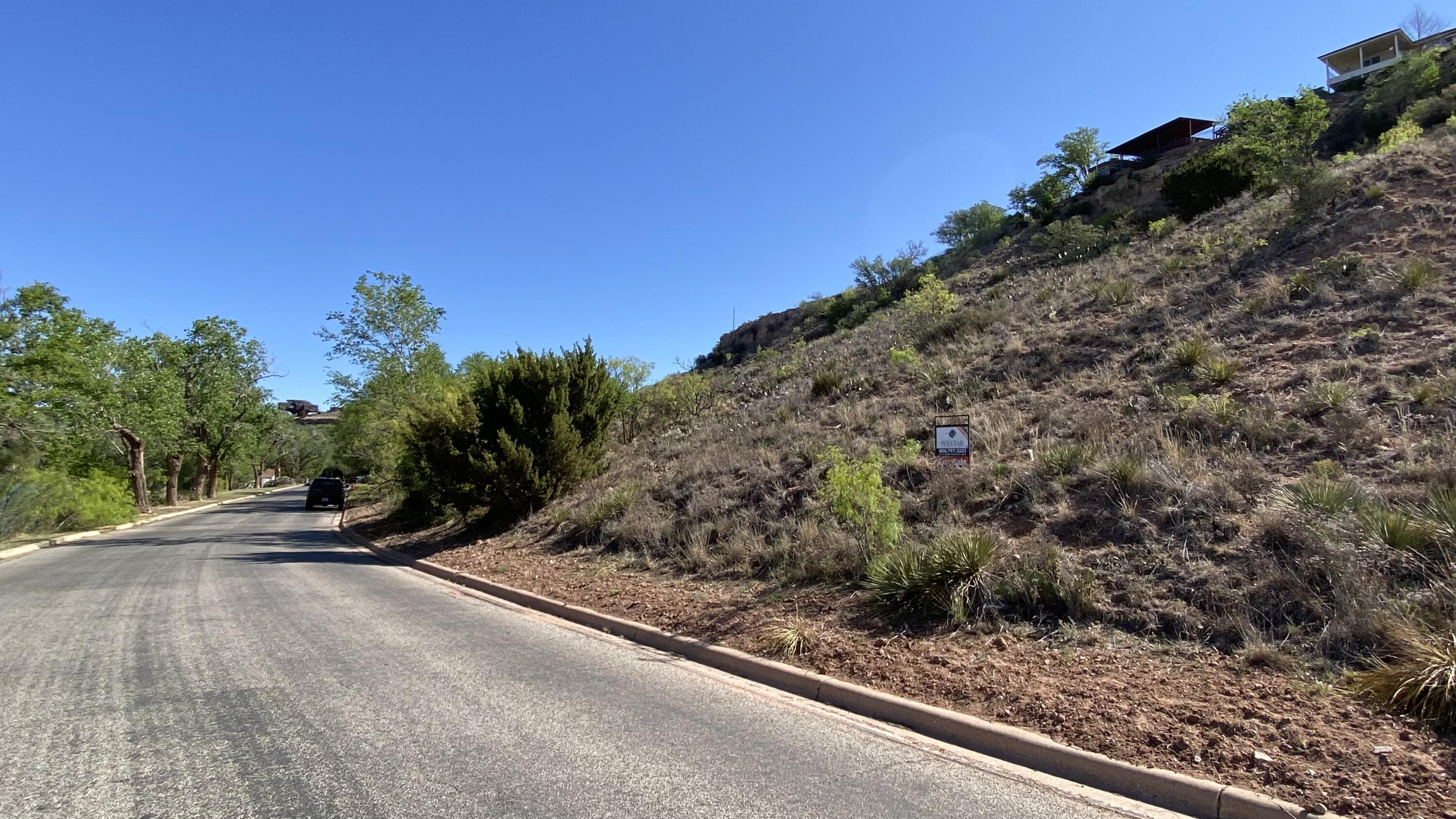 76 East Lakeshore Drive Ransom Canyon, TX 79366 - Photo 3 of 6 a view of a street with a wooden fence