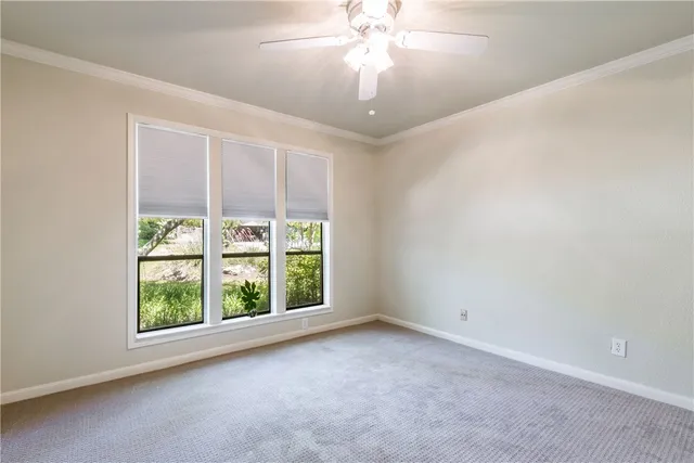 an empty room with windows and chandelier fan