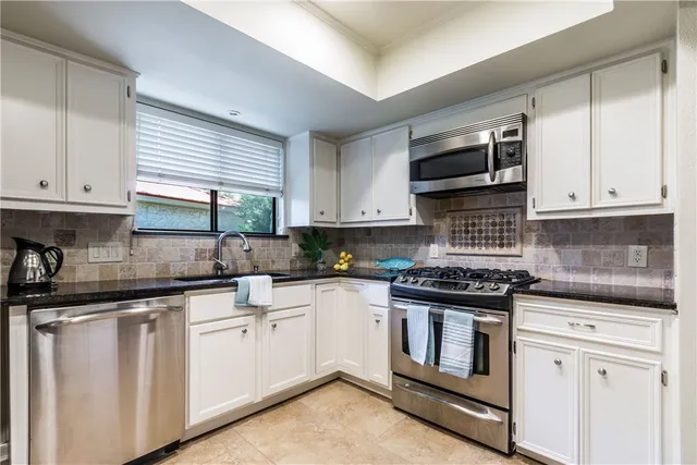 a kitchen with granite countertop white cabinets and appliances