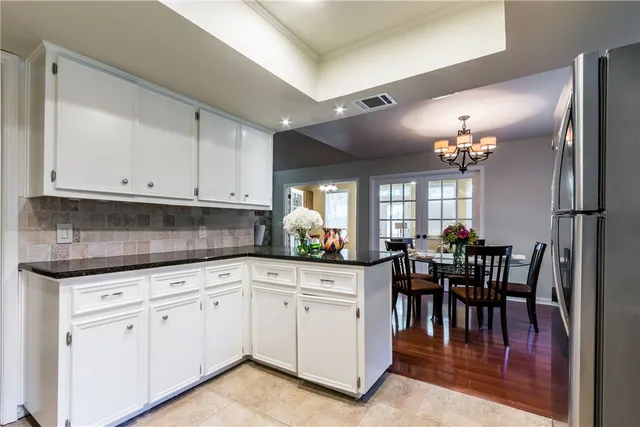 a kitchen with white cabinets and chandelier
