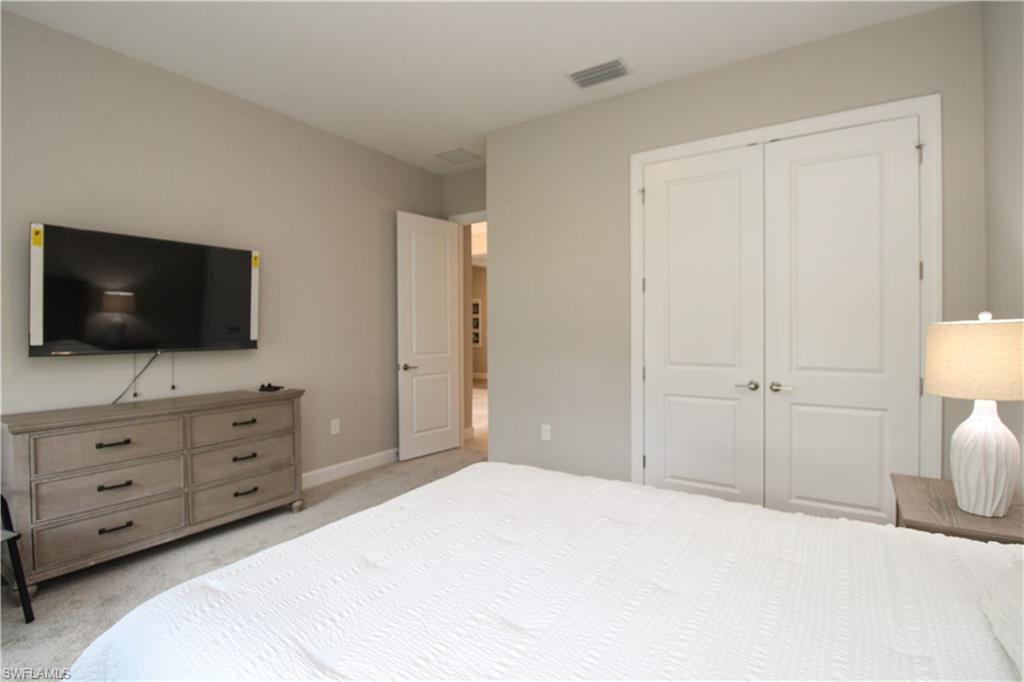 15765 Cortina Street Naples, FL 34114 - Photo 14 of 50 a bedroom with a bed and a flat screen tv in it