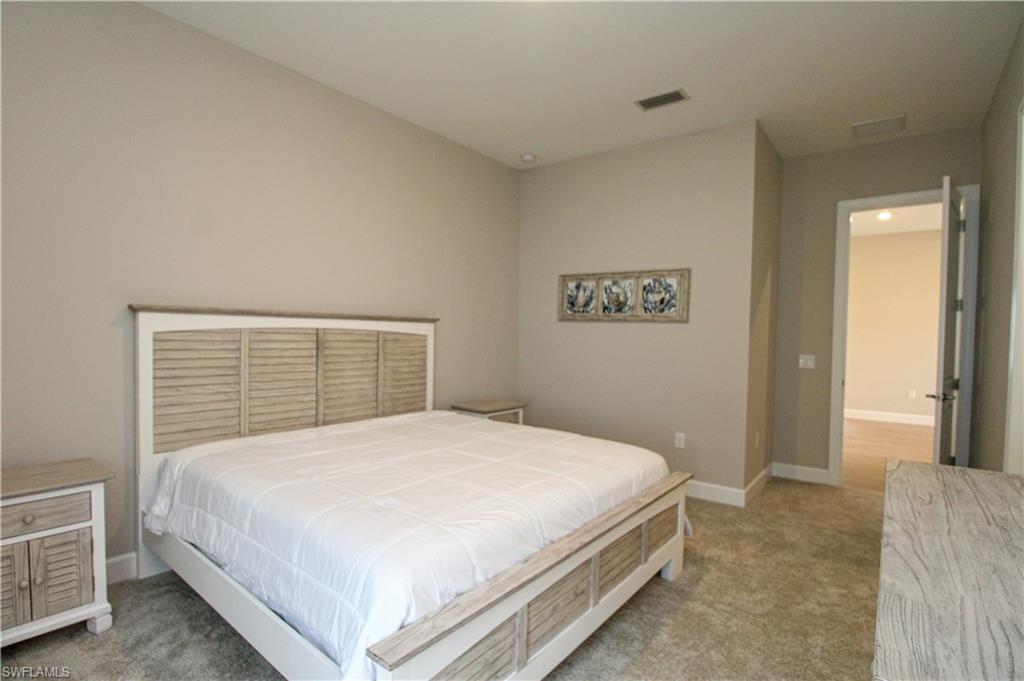 15765 Cortina Street Naples, FL 34114 - Photo 19 of 50 a bedroom with a large bed and a chandelier