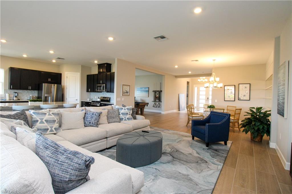 15765 Cortina Street Naples, FL 34114 - Photo 28 of 50 a living room with furniture wooden floor and a view of kitchen