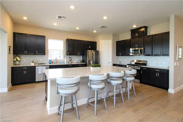 a kitchen with stainless steel appliances kitchen island granite countertop a sink and a stove top oven with wooden floor