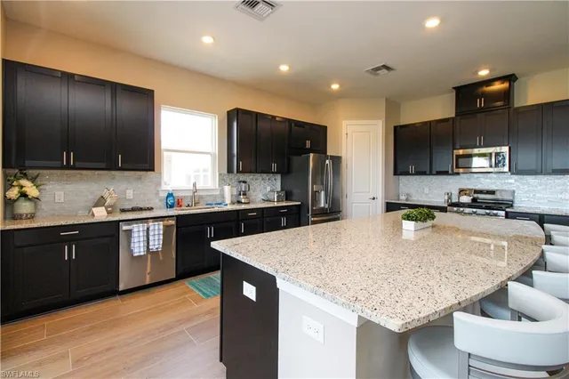 a large kitchen with kitchen island granite countertop wooden cabinets a refrigerator and a sink