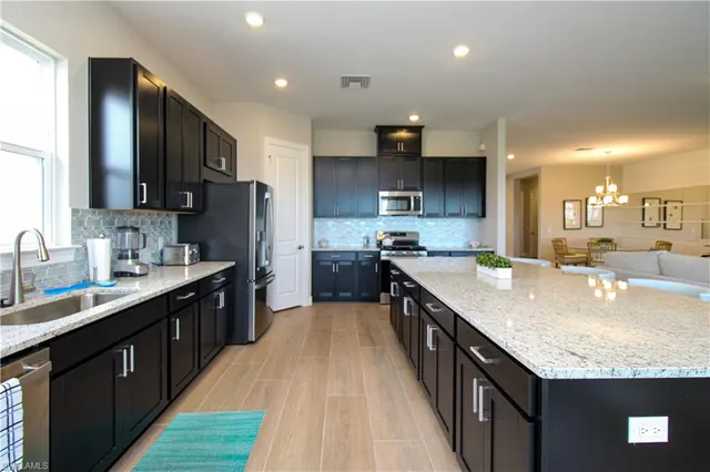 a large kitchen with stainless steel appliances granite countertop a sink stove and refrigerator