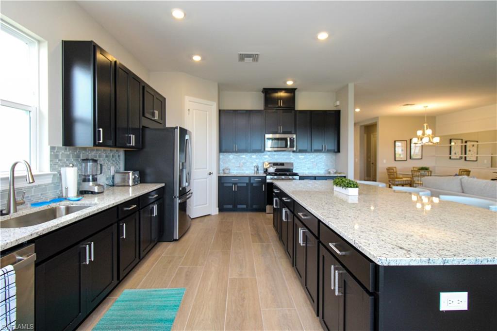15765 Cortina Street Naples, FL 34114 - Photo 31 of 50 a large kitchen with stainless steel appliances granite countertop a sink stove and refrigerator