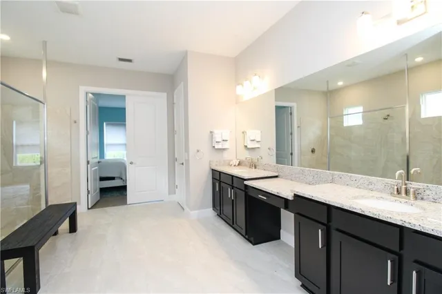 a bathroom with a granite countertop double vanity sink and mirror