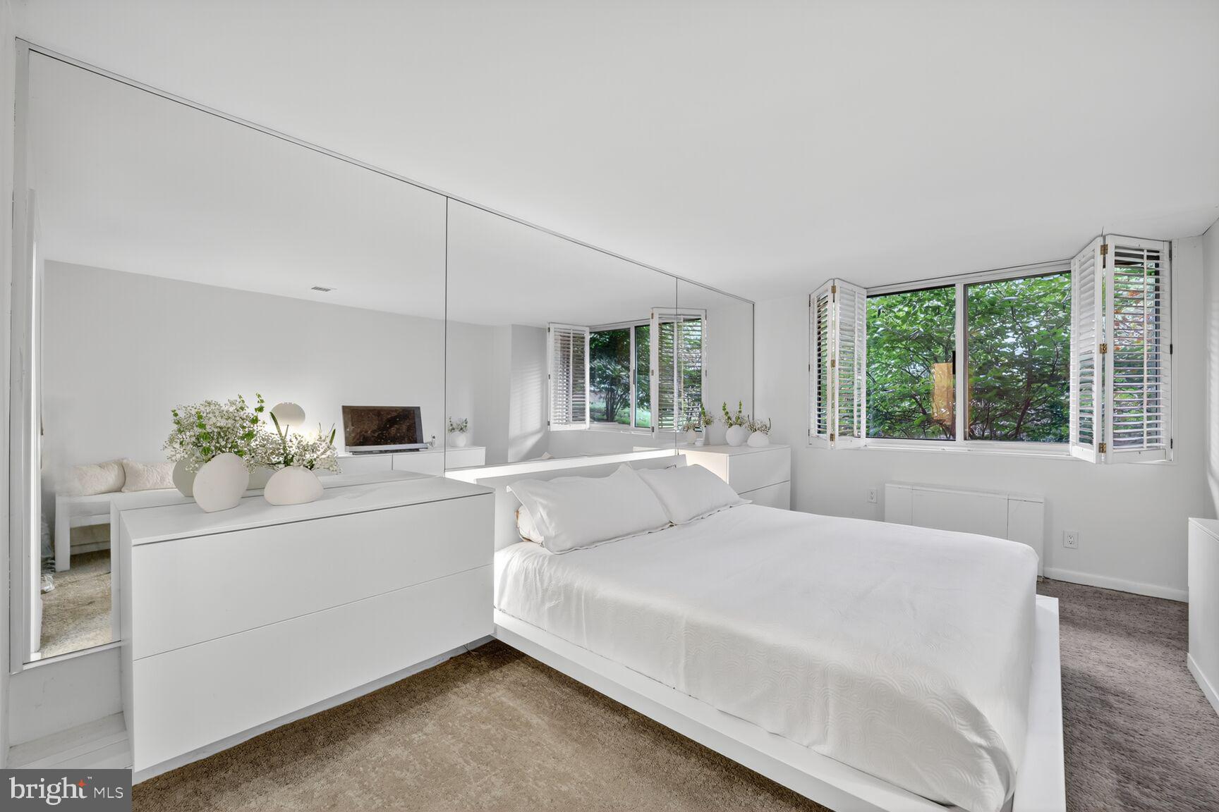 4100 Cathedral Avenue Northwest, Unit 615 Washington, DC 20016 - Photo 10 of 26 a room with a bed a potted plant on dresser and a window