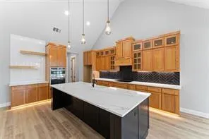 a large kitchen with kitchen island a sink dishwasher a stove and a refrigerator with wooden floor