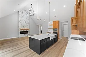 a large kitchen with kitchen island a stove a sink a chimney and wooden floor