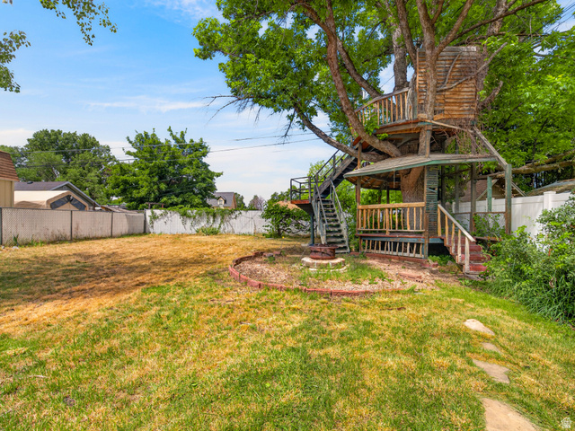 74 South 300 East Springville, UT 84663 - Photo 36 of 48 Multi-level treehouse with wood plank siding, multiple platforms, and integrated stairs, set within a spacious backyard featuring a grass lawn and perimeter fencing