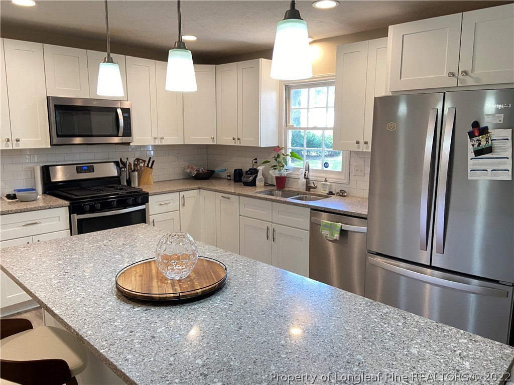 215 Rivenoak Drive Fayetteville, NC 28303 - Photo 9 of 21 a kitchen with stainless steel appliances granite countertop a sink a stove a refrigerator a microwave oven with cabinets and wooden floor