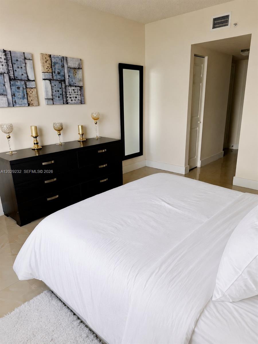 17100 North Bay Road, Unit 1605 Sunny Isles Beach, FL 33160 - Photo 14 of 52 a bedroom with a bed and a mirror