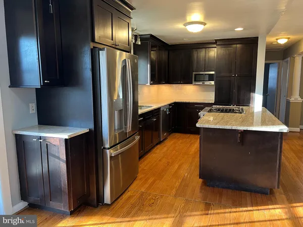 a kitchen with stainless steel appliances granite countertop a stove a sink dishwasher and a refrigerator with wooden floor