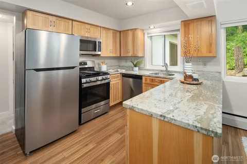 a kitchen with stainless steel appliances granite countertop a refrigerator a stove top oven a sink and dishwasher with wooden floor