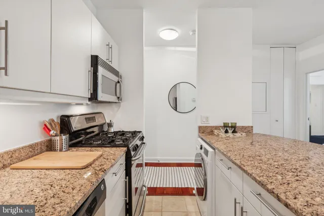 a kitchen with granite countertop a sink a stove and cabinets