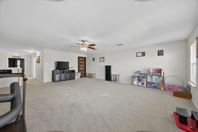 an empty room with a chandelier fan and windows