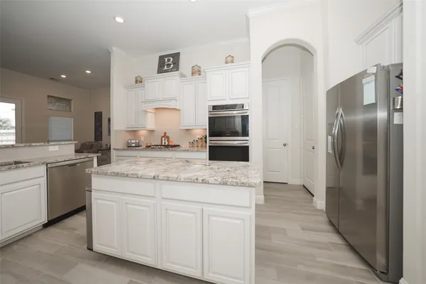 a hall with stainless steel appliances granite countertop a refrigerator and a stove top oven