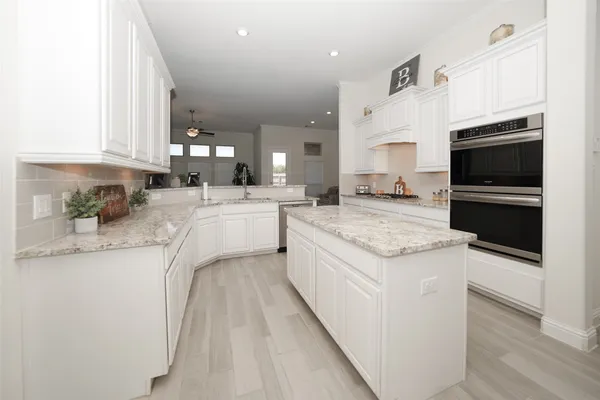 a large kitchen with stainless steel appliances kitchen island granite countertop a lot of counter space and wooden floor