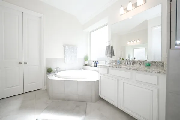 a spacious bathroom with a double vanity sink mirror and bathtub