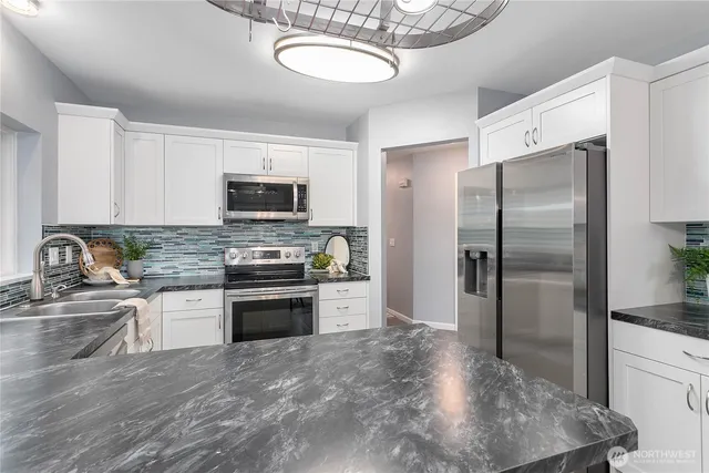 a kitchen with stainless steel appliances granite countertop a stove a refrigerator and a sink