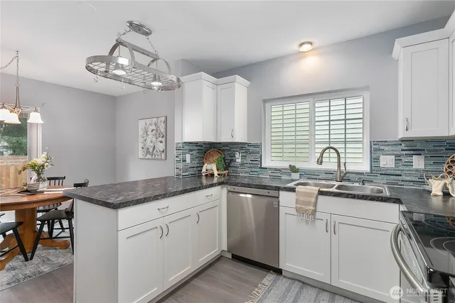 a kitchen with a sink dishwasher a stove a microwave oven and a dining table with wooden floor