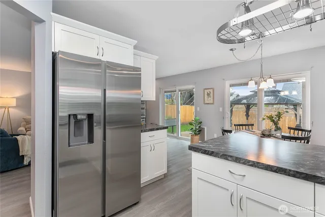 a kitchen with granite countertop stainless steel appliances a chandelier counter space and wooden floor