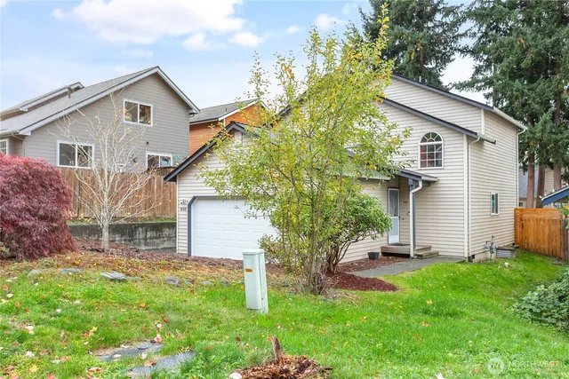 a view of a white house with a small yard and large trees