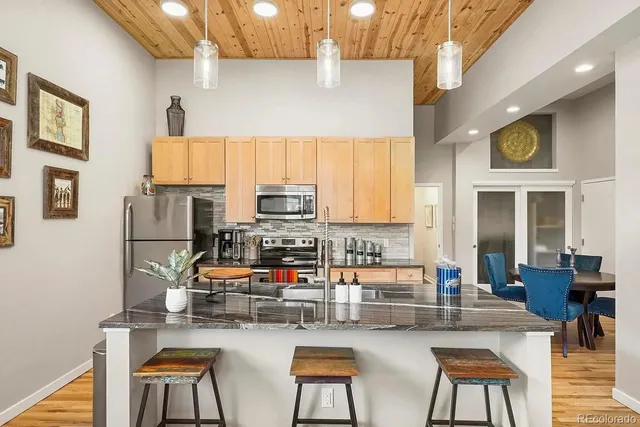 a kitchen with stainless steel appliances a stove a refrigerator a dining table and chairs with wooden floor