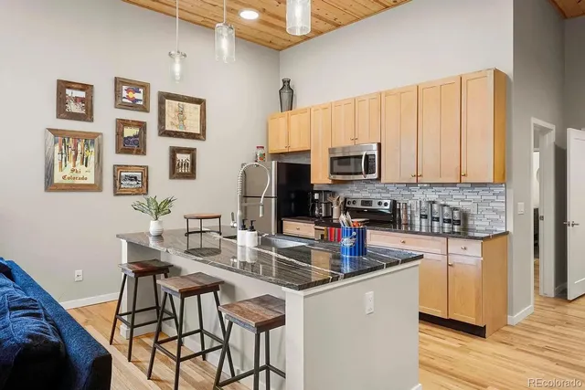 a kitchen with stainless steel appliances granite countertop a stove a sink dishwasher and a refrigerator with wooden floor