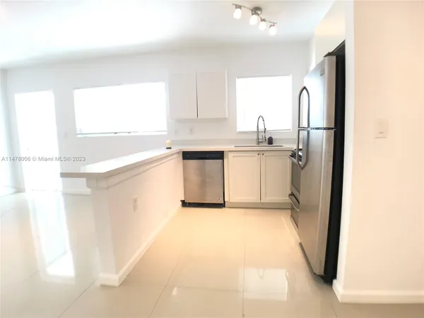 a kitchen with a refrigerator a sink dishwasher a stove and white cabinets with wooden floor