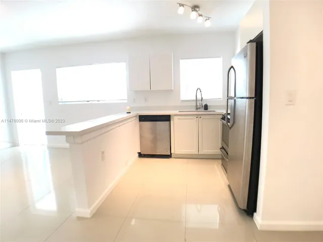 a kitchen with a refrigerator a sink dishwasher a stove and white cabinets with wooden floor