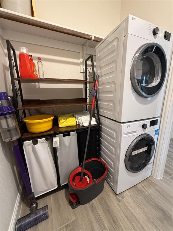 5212 Troupe Road McKinney, TX 75071 - Photo 12 of 38 Dedicated laundry space featuring stacked appliances, a built-in hanging rod, and wood-finish flooring