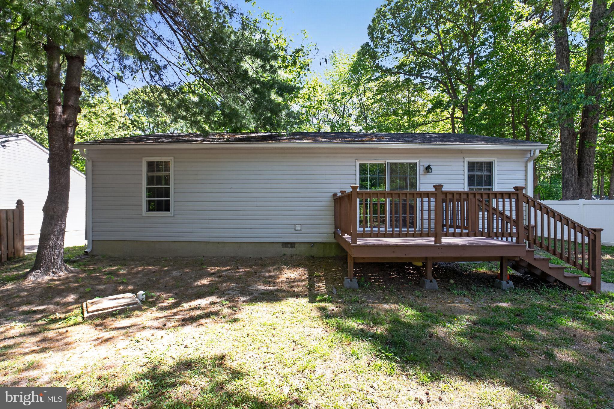11789 Little Cove Point Road Lusby, MD 20657 - Photo 5 of 16 a view of a house with a wooden deck and a yard