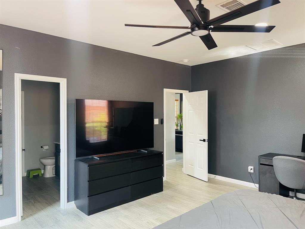516 Angela Lane Euless, TX 76039 - Photo 18 of 39 Bedroom featuring light wood-type flooring, a desk, ensuite bathroom, and a ceiling fan