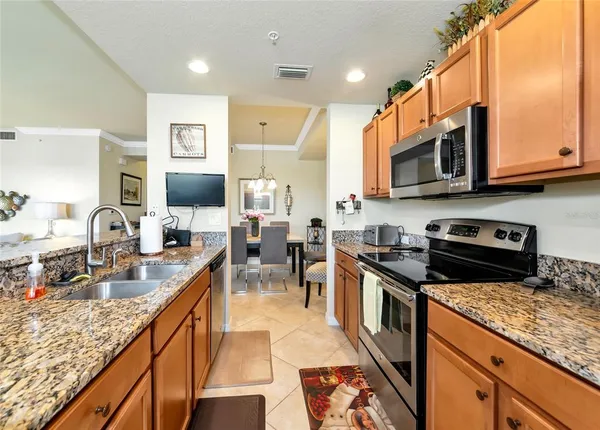 a kitchen with stainless steel appliances granite countertop a stove top oven a sink dishwasher a dining table and chairs with wooden floor