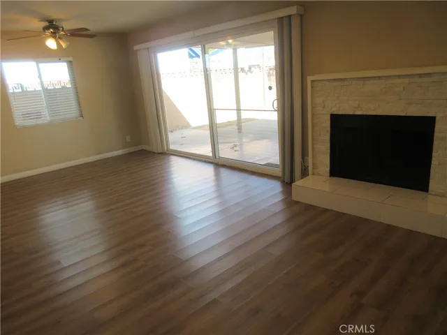 an empty room with wooden floor fireplace and windows