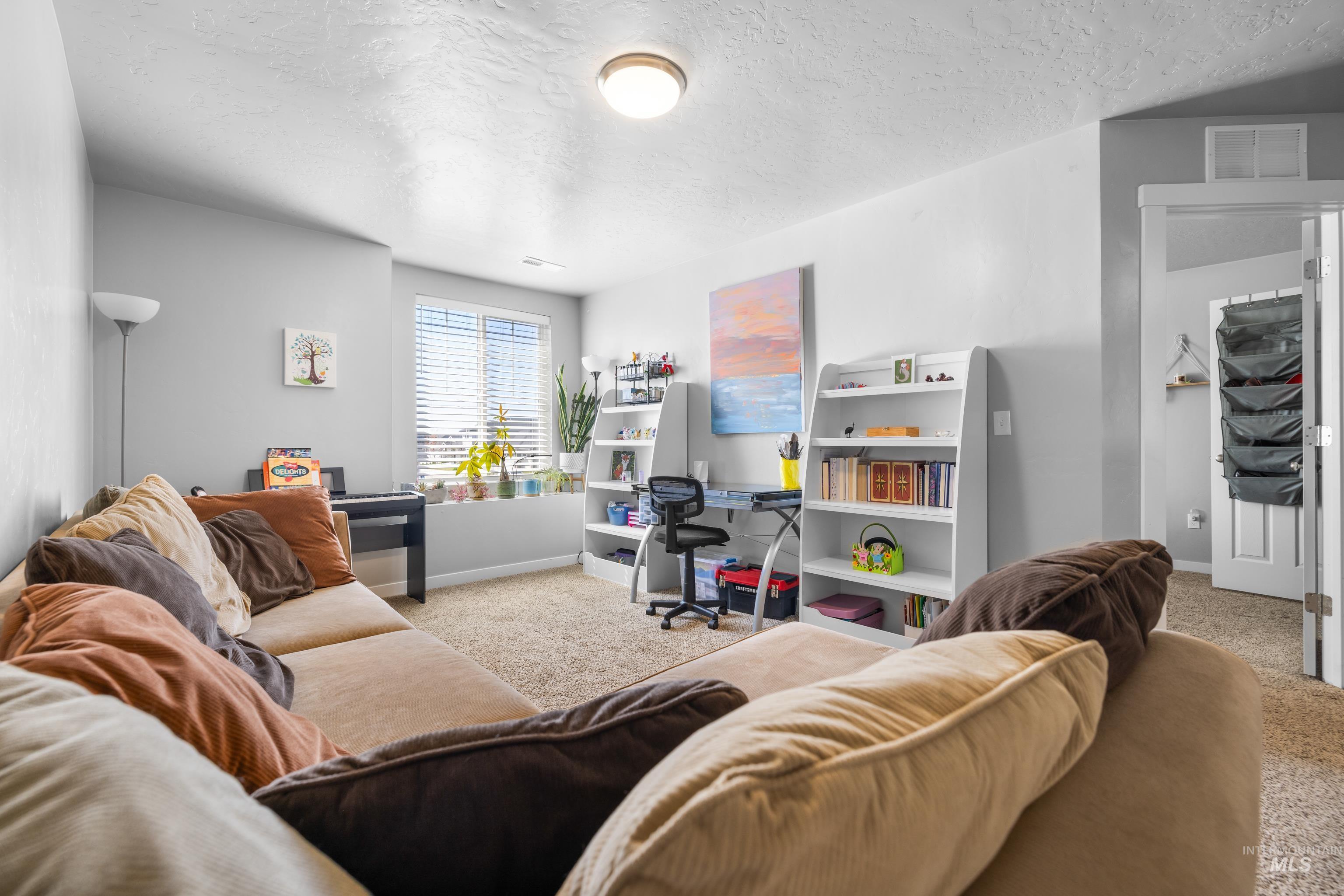 6988 West Spur Street Boise, ID 83709 - Photo 18 of 37 Carpeted living room featuring a textured ceiling and baseboards