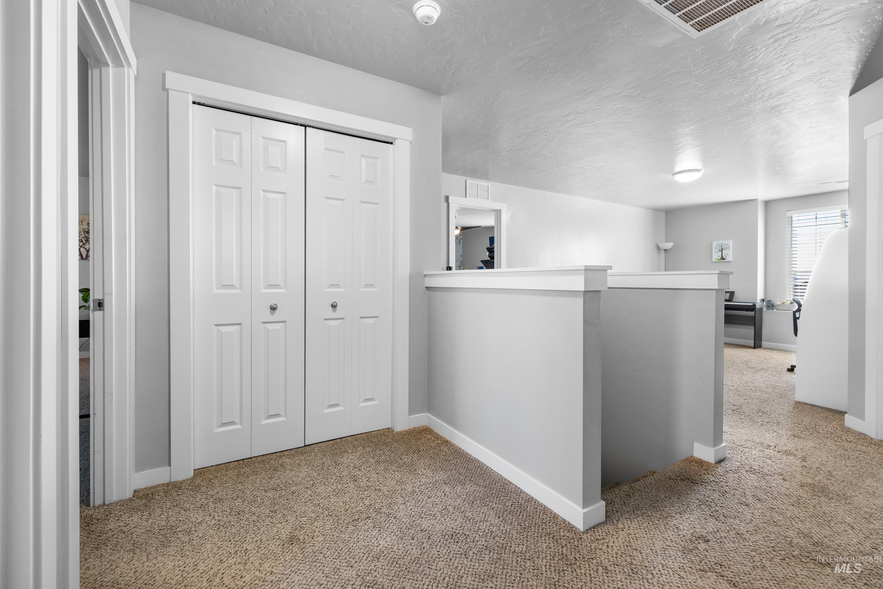 6988 West Spur Street Boise, ID 83709 - Photo 26 of 37 Hall featuring carpet flooring, a textured ceiling, and an upstairs landing