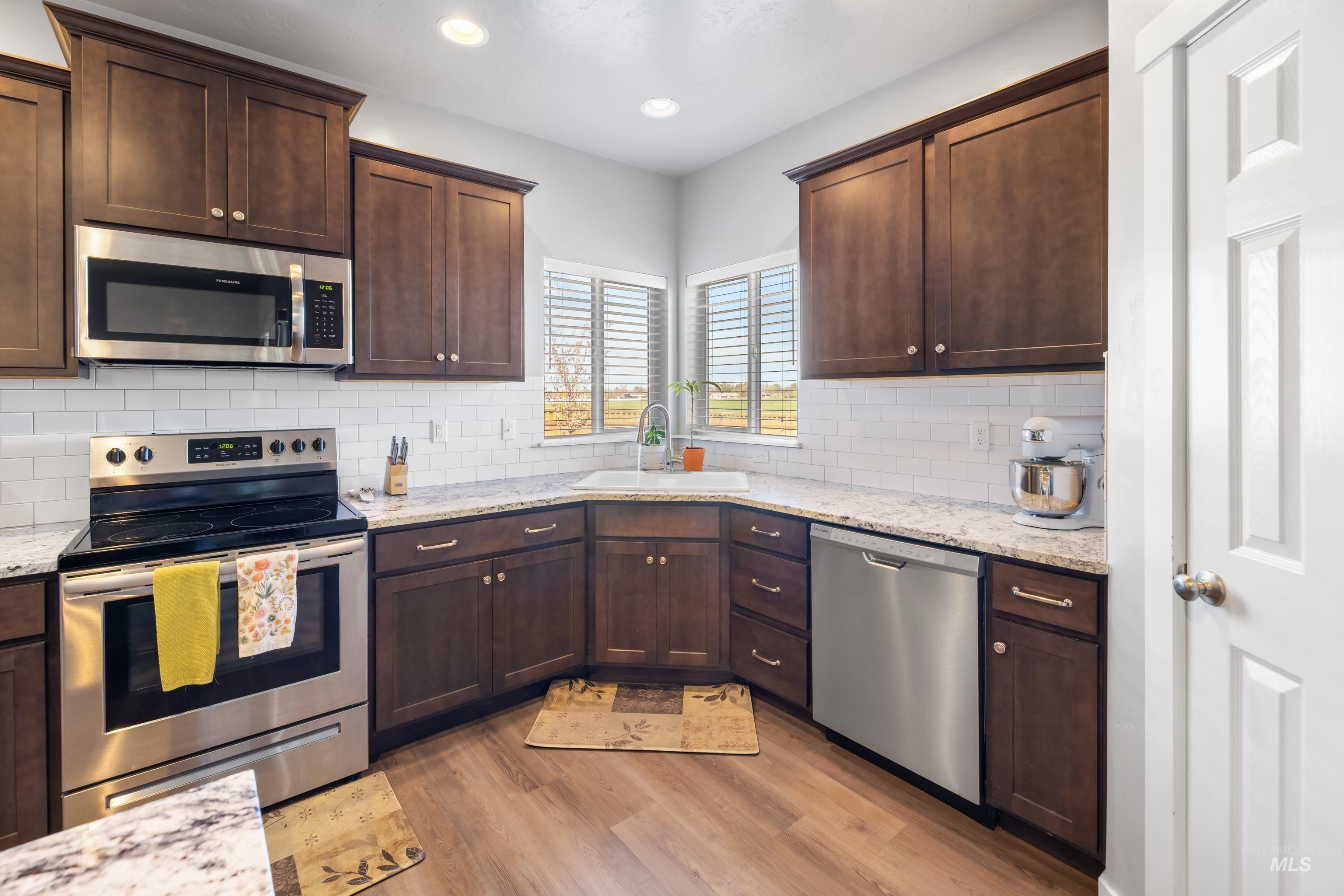 6988 West Spur Street Boise, ID 83709 - Photo 8 of 37 Kitchen featuring stainless steel appliances, dark wood finish cabinetry, light stone countertops, and recessed lighting