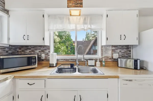 a living room with couches and a flat screen tv with kitchen view