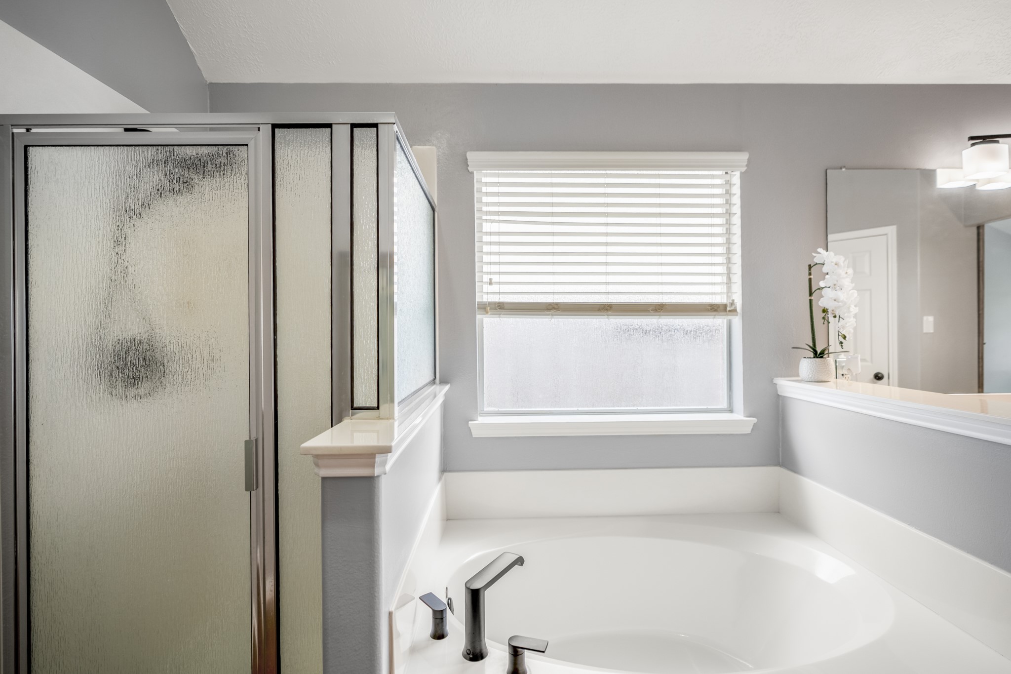 3411 Utah Beach Court Spring, TX 77388 - Photo 22 of 50 Continuing through the primary bath, the soaking tub sits beneath a wide window with the separate shower nearby, giving the suite a practical setup with both options in place. The vanity area from the previous view sits just behind this space, keeping the bath easy to move through while still feeling nicely defined.