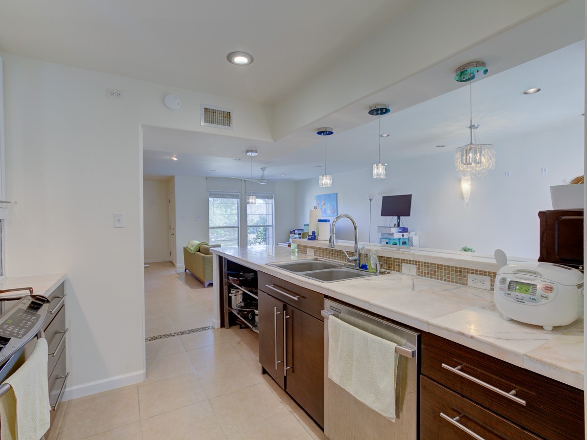 710 Castle Ridge Road, Unit B Austin, TX 78746 - Photo 9 of 27 An open concept kitchen features warm wood cabinetry, stainless appliances, and convenient pass-through to the living area.
