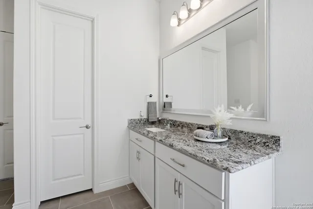 a bathroom with a granite countertop sink and a mirror