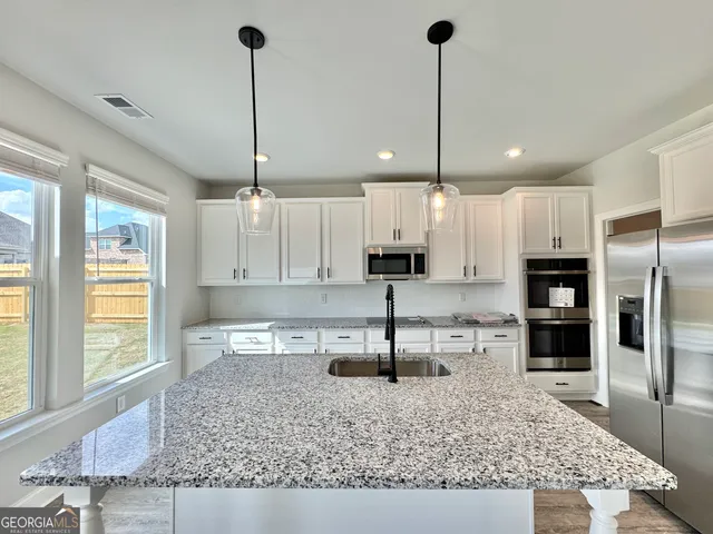 a kitchen with stainless steel appliances granite countertop a sink a stove and a refrigerator
