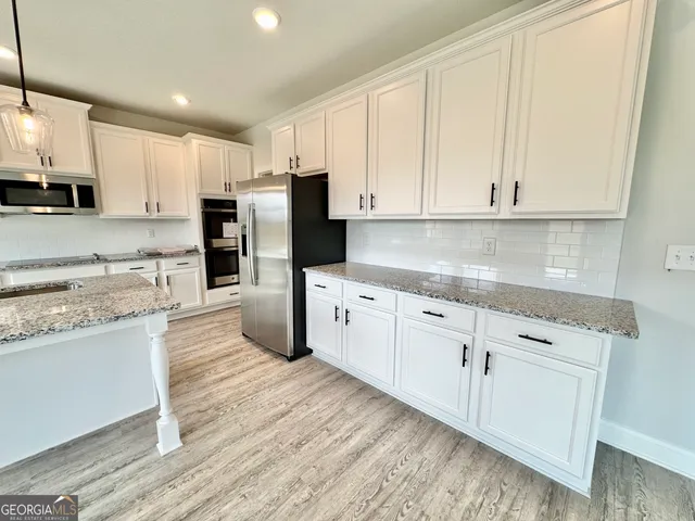 a kitchen with granite countertop kitchen island wooden floors granite counter tops and white appliances
