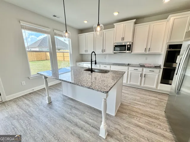 a kitchen with stainless steel appliances granite countertop a sink a stove top oven a counter space and cabinets