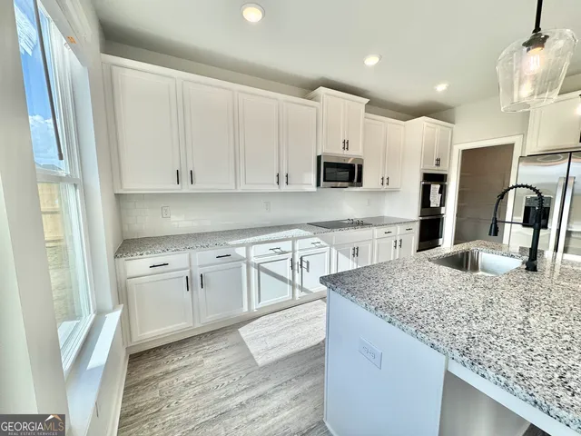 a kitchen with granite countertop white cabinets and stainless steel appliances
