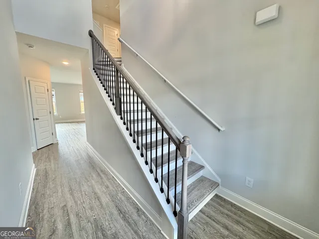 a view of staircase with wooden floor and white walls